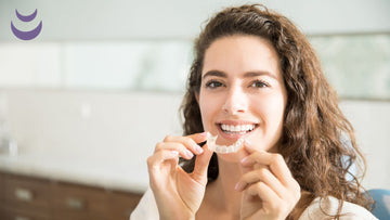 Woman with brown hair smiling while putting in a retainer
