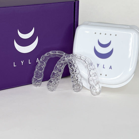 Clear aligners with a white case on a purple Lyla box.